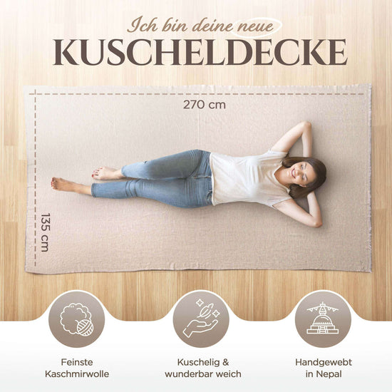 Eine Frau mit braunen Haaren liegt entspannt auf einer beige farbenen Kaschmirdecke, die 270 x 135 cm groß ist, auf Holzboden. Oben steht „Ich bin deine neue Kuscheldecke“. Darunter sieht man drei Symbole: eines für Kaschmirwolle, eines für Weichheit, und eines für Handarbeit in Nepal. Darunter jeweils die Texte „Feinste Kaschmirwolle“, „Kuschelig & wunderbar weich“ und „Handgewebt in Nepal“.